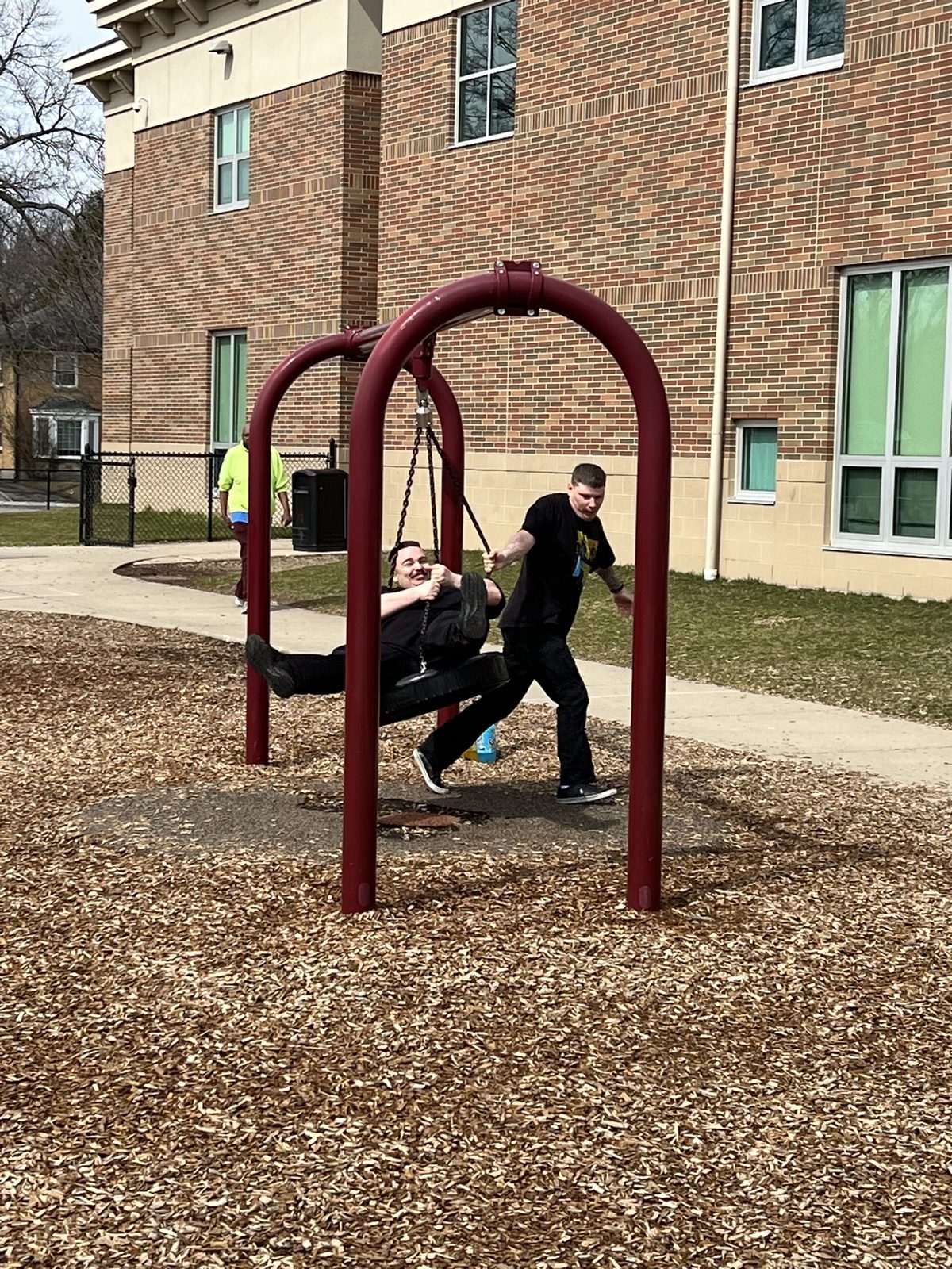 A Giddings AFC resident smiling on a playground swing